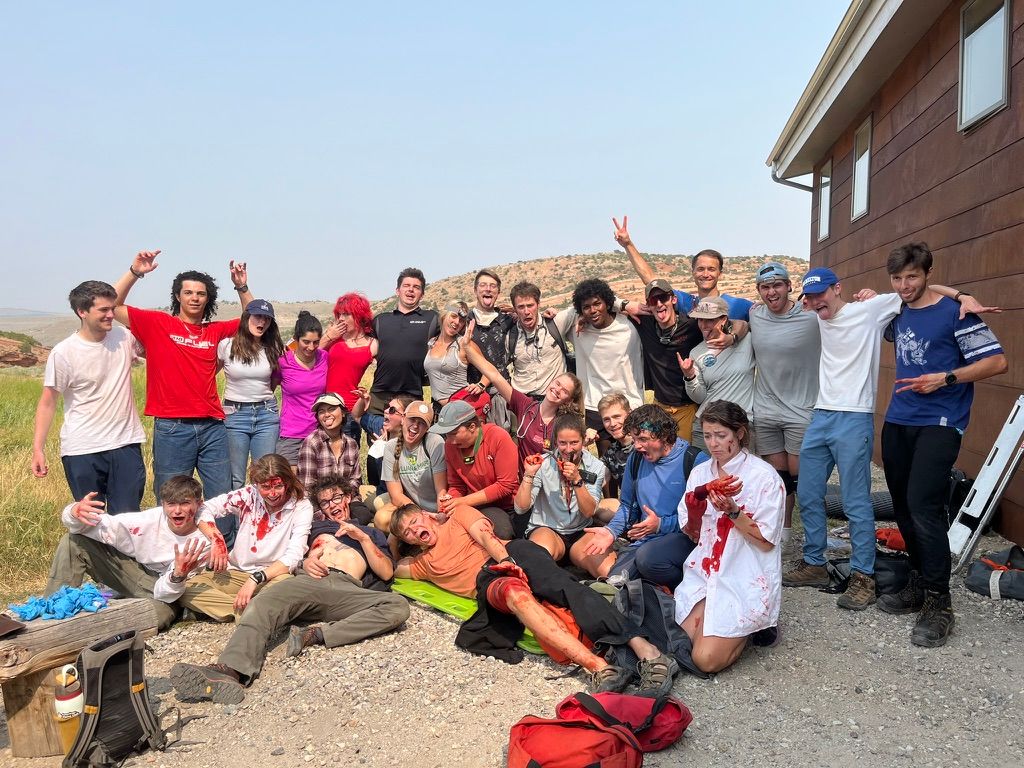A group of NOLS WEMT classmates posing after a moulage exercise, covered in fake blood and gore